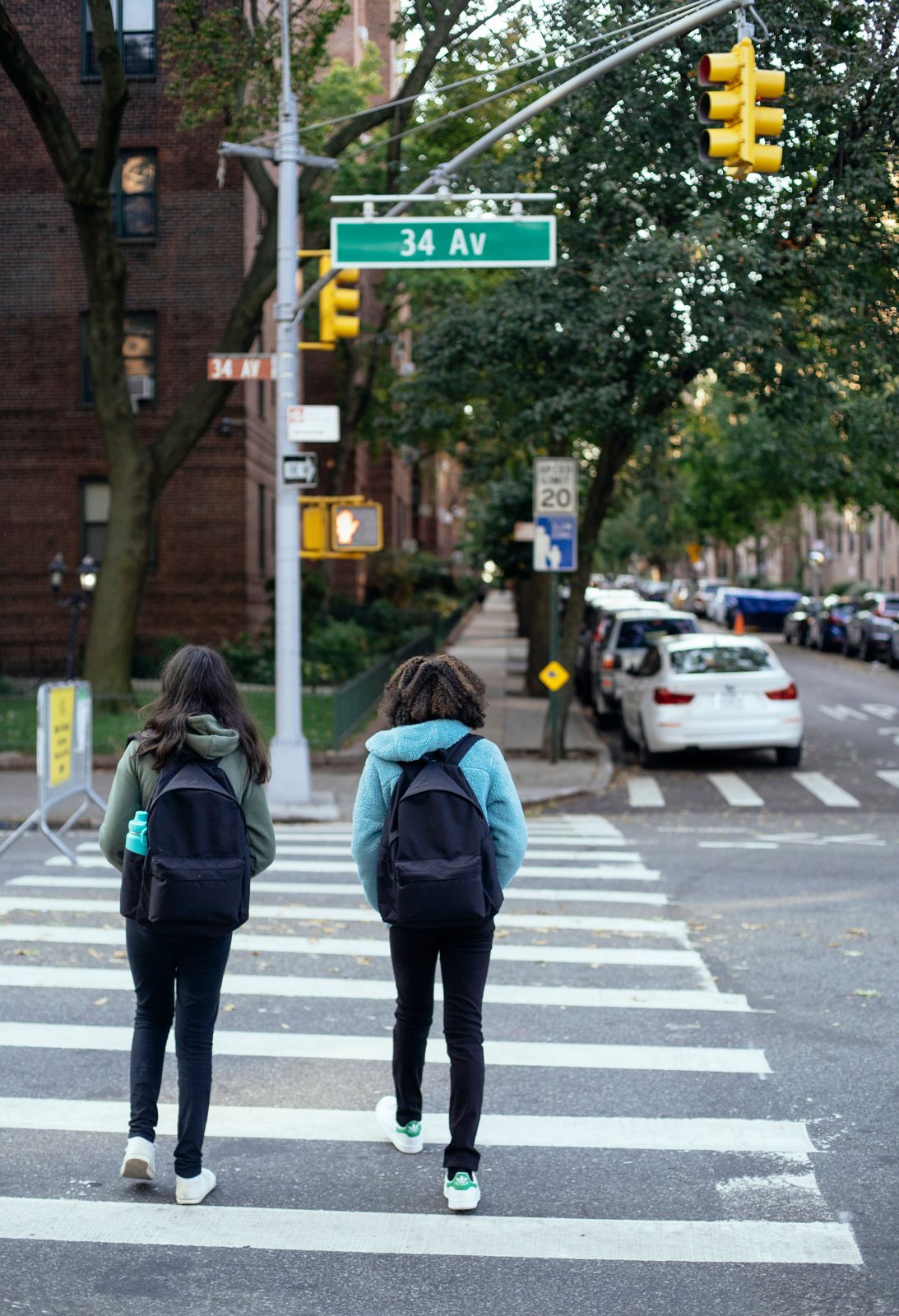 Two kids with backpacks crossing a NYC street on the way to school